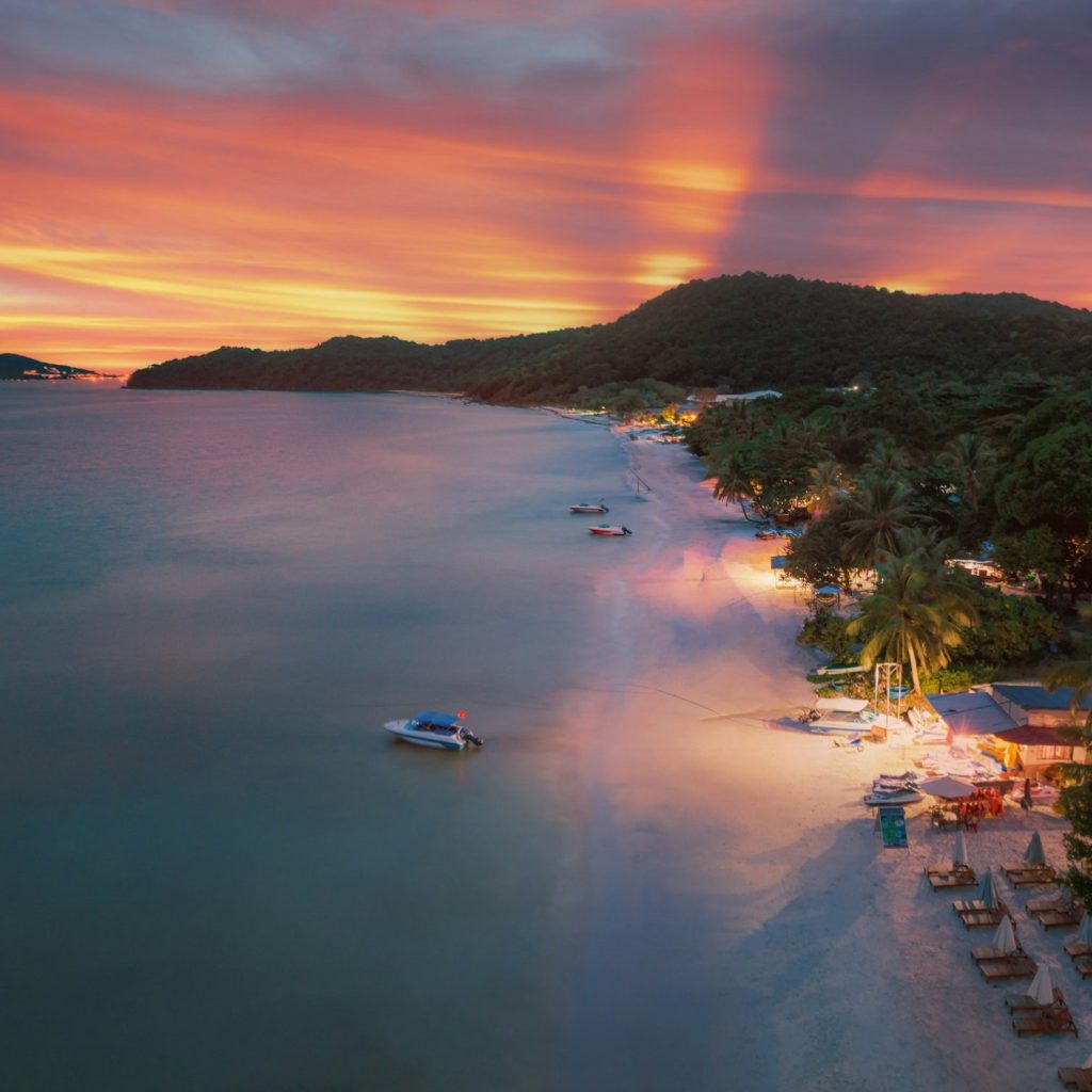 a beach at sunset with a boat in the water