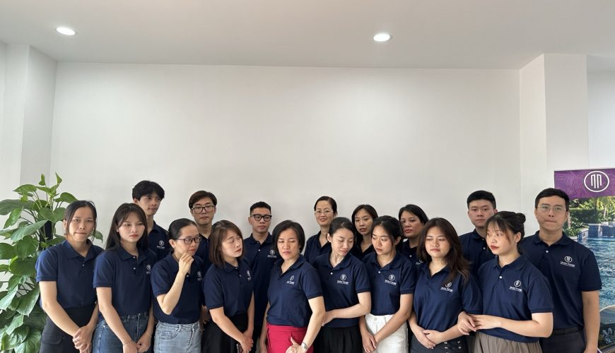 Tập thể nhân viên Metta Voyage bên standee công ty