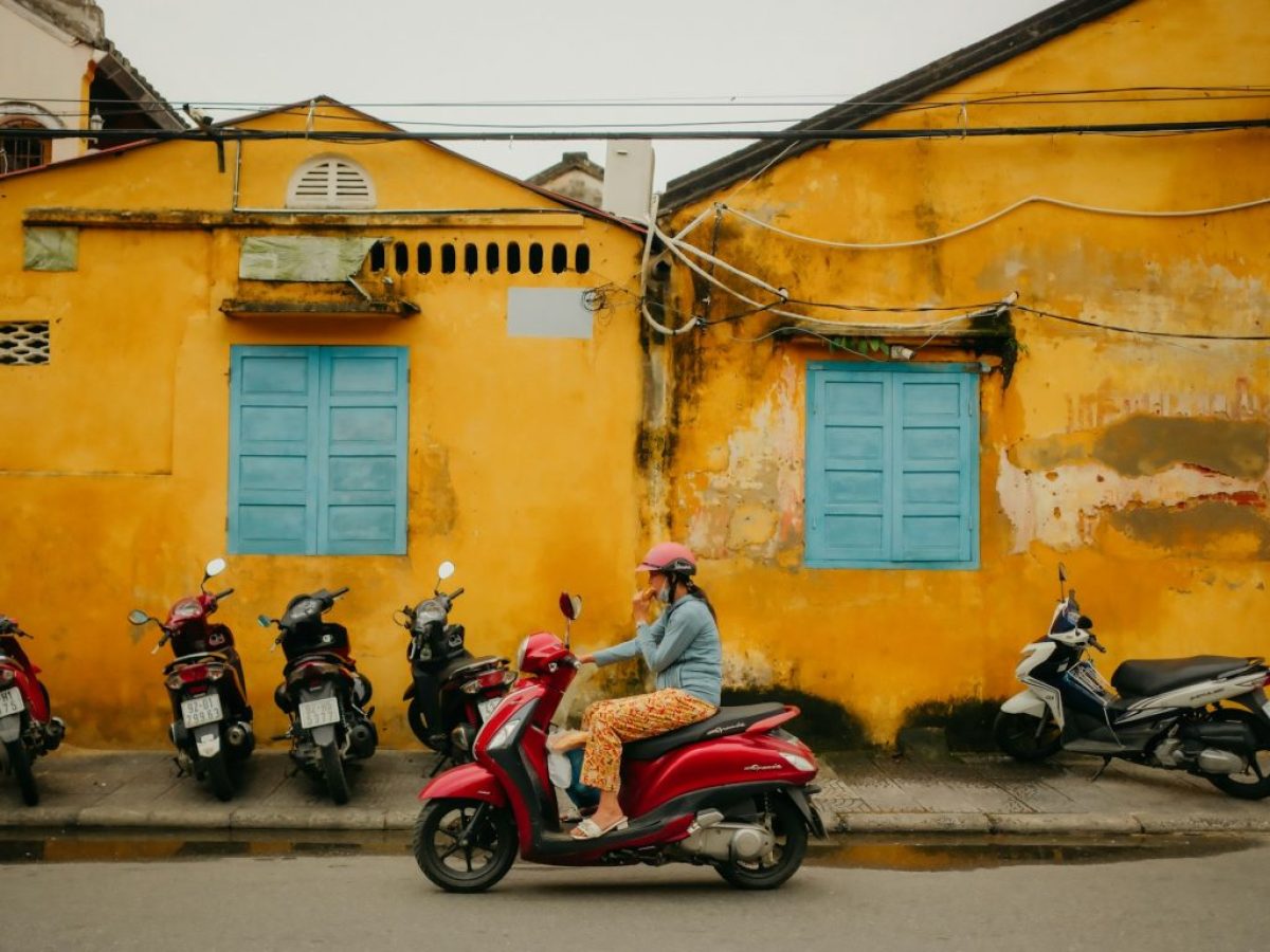 A group of motor scooters parked in front of a yellow building