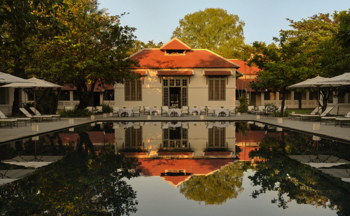 Amantaka's colonial-style restaurant building reflected in the main pool at dusk, Luang Prabang