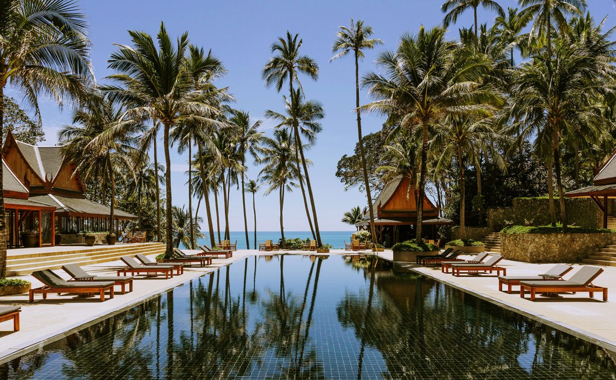 Amanpuri's main pool framed by coconut palms and Thai-style pavilions, the Andaman Sea beyond