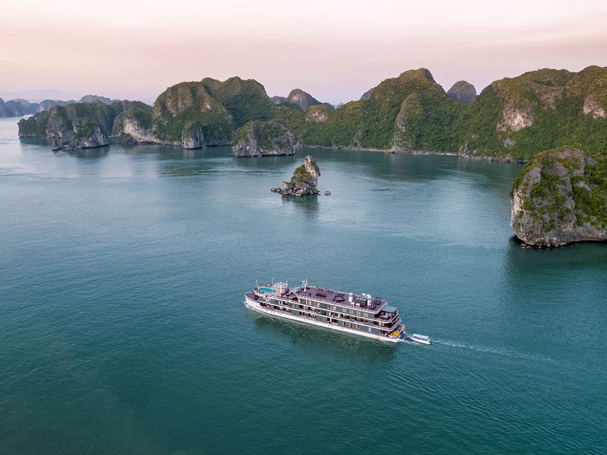 Heritage Cruises Binh Chuan sailing between limestone islands of Lan Ha Bay at dusk, aerial view