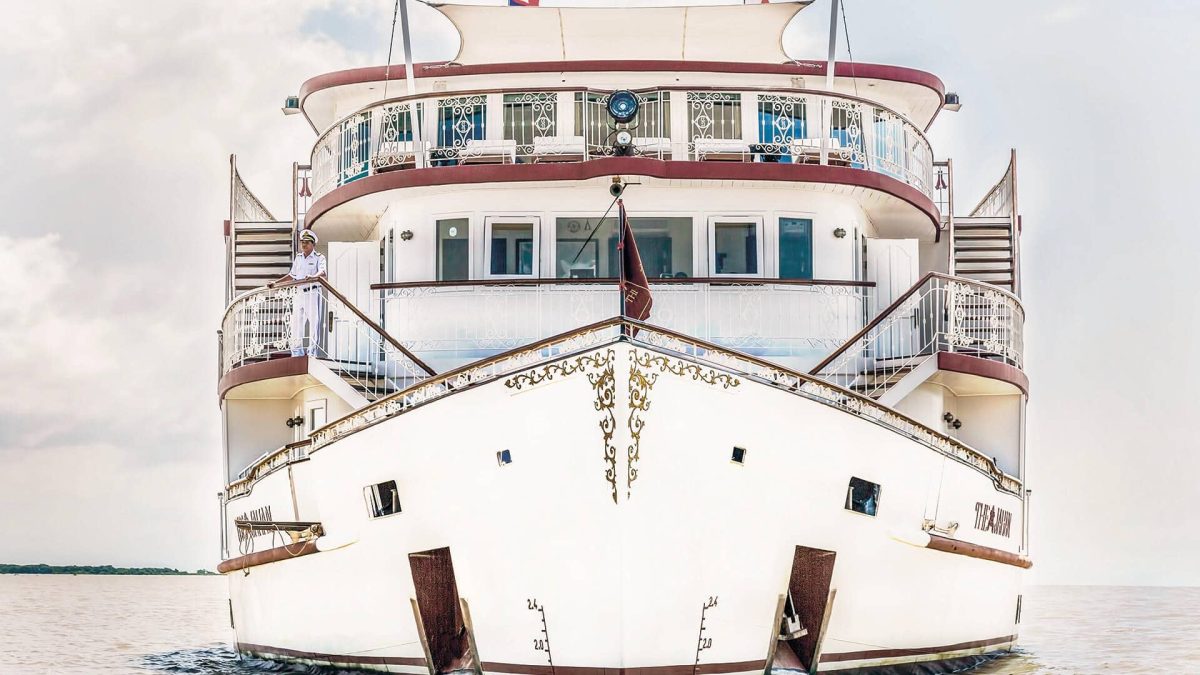 Bow of Heritage Line The Jahan on the Mekong, white hull with ornate railings and an officer on deck