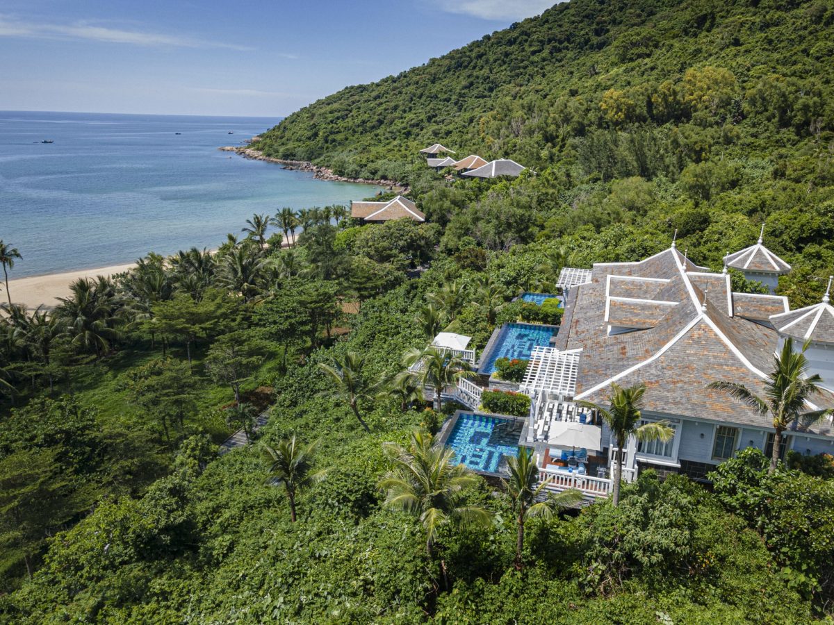 Aerial view of InterContinental Danang Sun Peninsula Resort villas on a forested hillside above a private bay