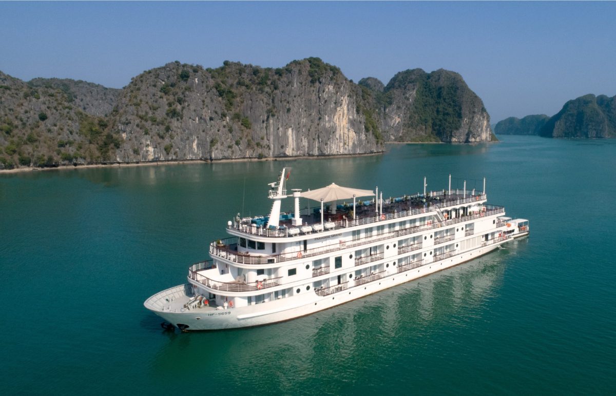 Paradise Grand cruise ship with its large sundeck in front of Lan Ha Bay limestone cliffs