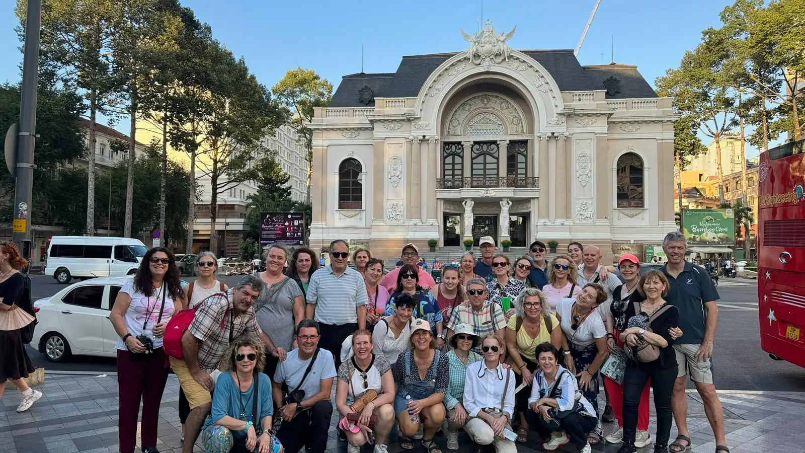A large Metta Voyage group smiling in front of the Saigon Opera House